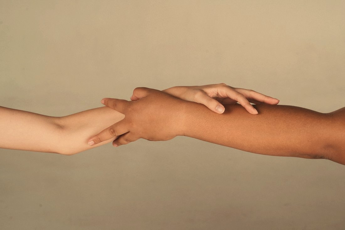 Two hands of different skin tones clasped together
